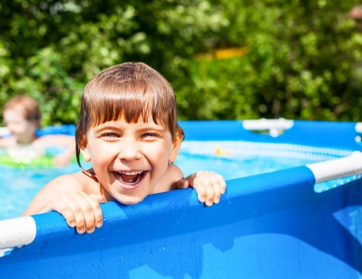 little boy playing in a swimming pool in summer