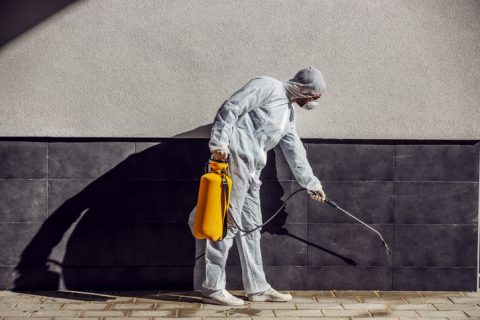 Man cleaning around outside of a building