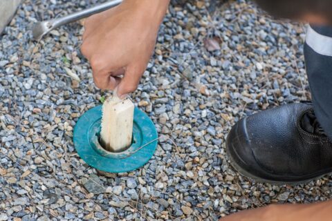 termite control technician applies treatment in ground