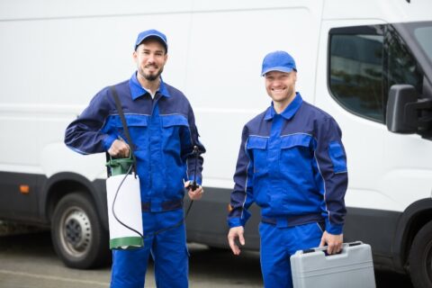 Portrait Of Two Happy Male Pest Control Workers With Toolbox