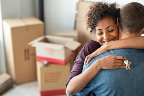 Young woman holding home keys while hugging boyfriend